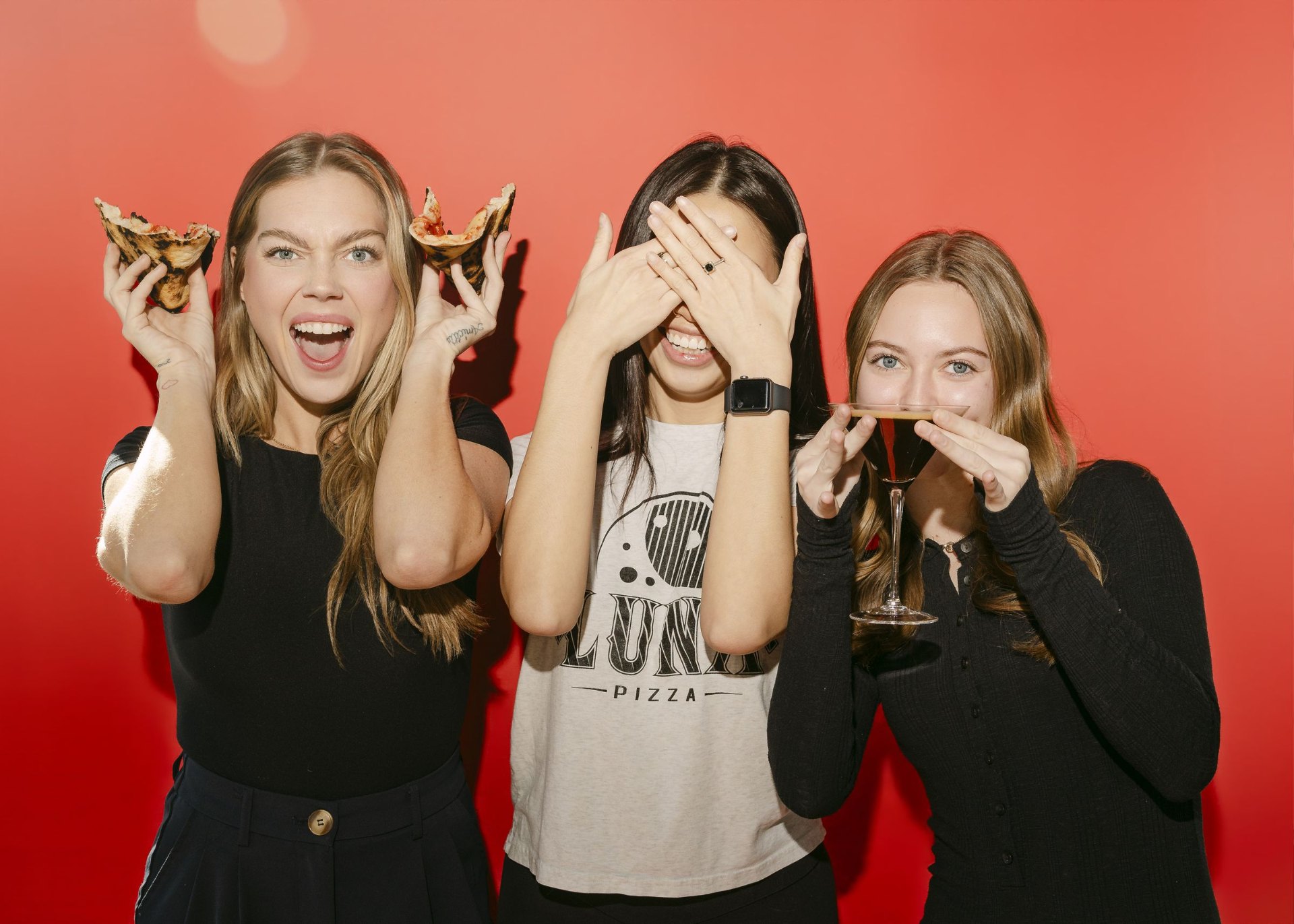 Three friends with pizza and cocktails